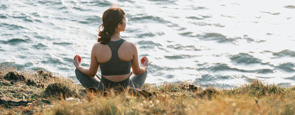 A girl practicing meditation & yoga by the ocean, symbolizing mind-body alignment, inner peace, and spiritual wellness. Represents the power of mindfulness to transform urban lifestyles.